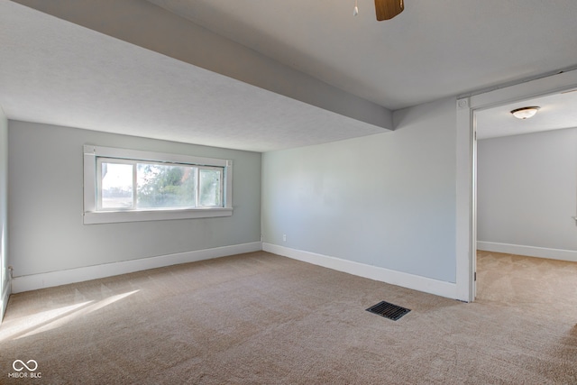 carpeted spare room with visible vents, ceiling fan, and baseboards