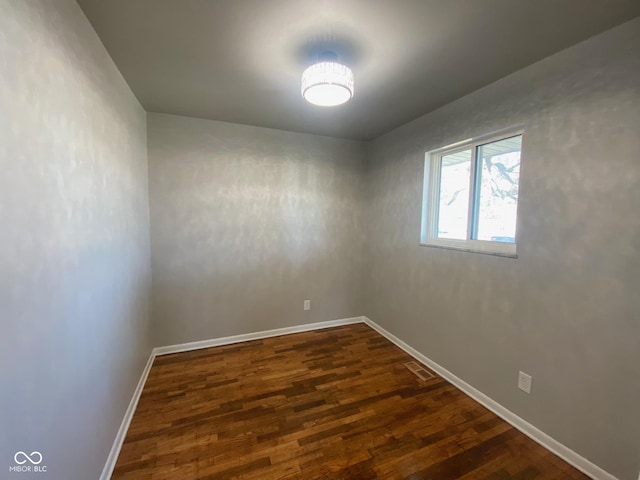 unfurnished room with visible vents, dark wood-type flooring, and baseboards