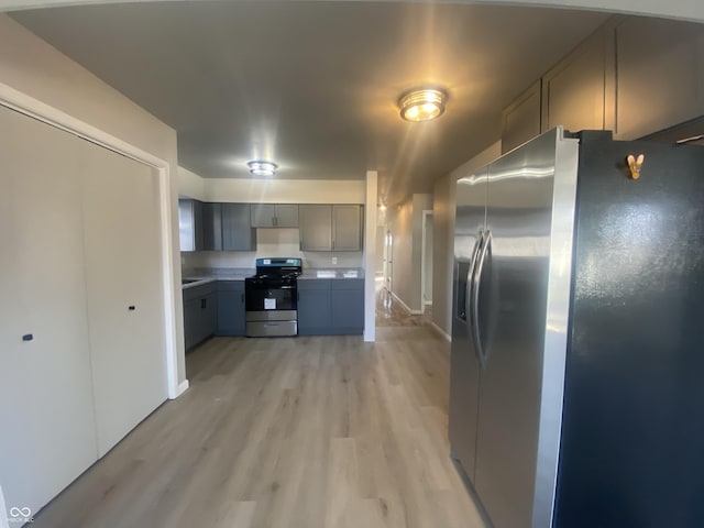 kitchen featuring light wood-style flooring, appliances with stainless steel finishes, gray cabinets, and light countertops