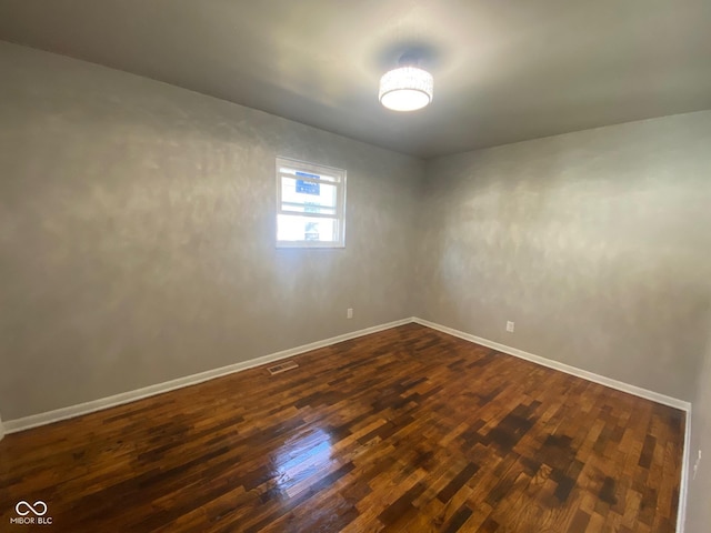 spare room with visible vents, dark wood-type flooring, and baseboards