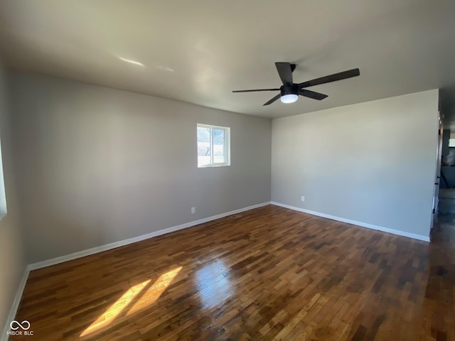 unfurnished room with dark wood finished floors, a ceiling fan, and baseboards