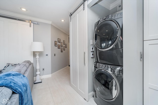 washroom with laundry area, crown molding, a barn door, and stacked washer and dryer