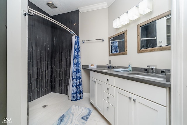 bathroom with double vanity, tile patterned floors, a tile shower, and a sink