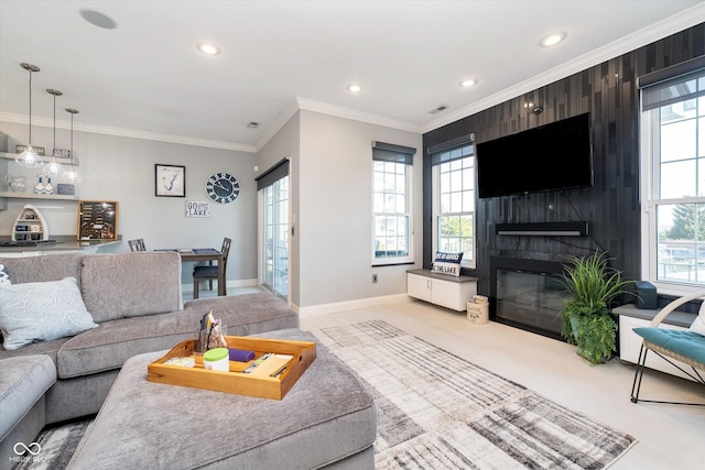 living area with a large fireplace, plenty of natural light, baseboards, and ornamental molding