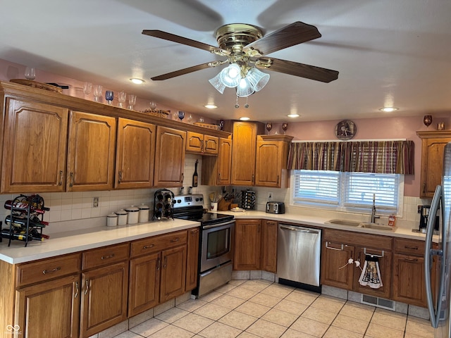 kitchen featuring light countertops, decorative backsplash, brown cabinetry, stainless steel appliances, and a sink