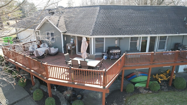 rear view of house featuring outdoor dining space, a wooden deck, and a shingled roof