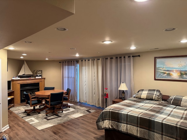 bedroom featuring recessed lighting, wood finished floors, and a fireplace