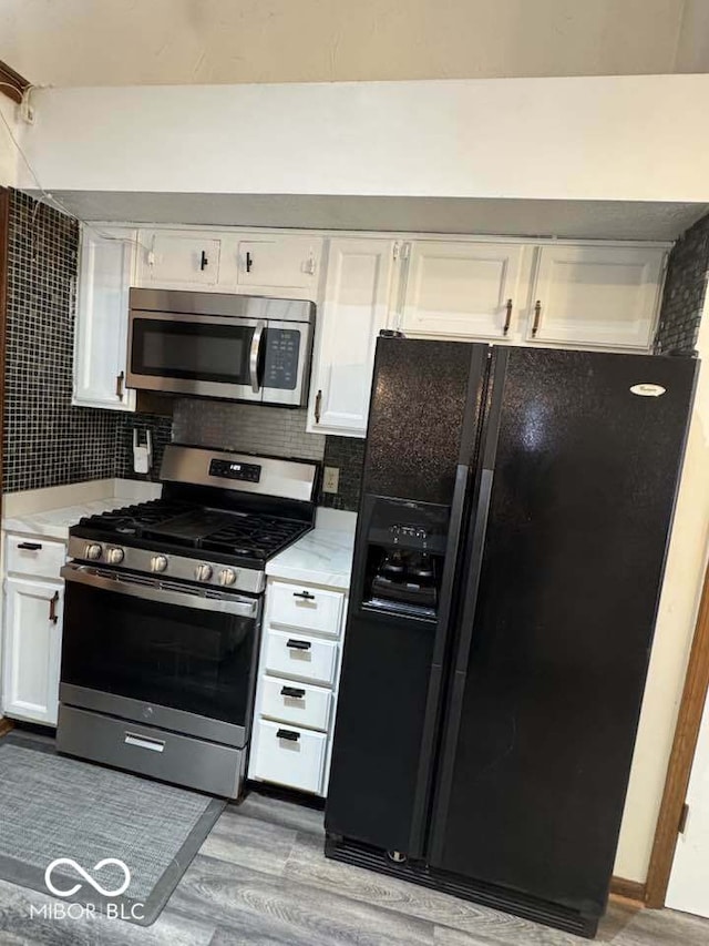 kitchen featuring tasteful backsplash, appliances with stainless steel finishes, white cabinets, and light countertops