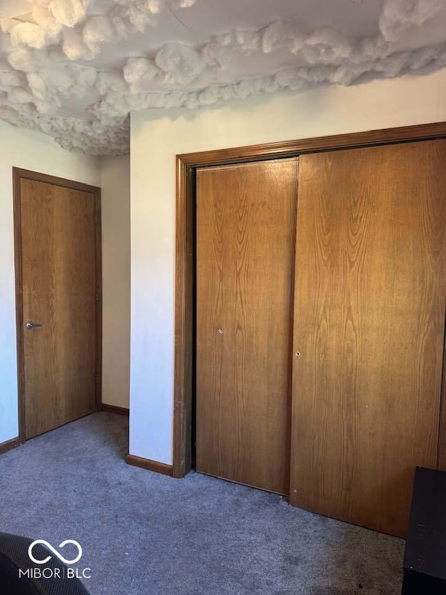 unfurnished bedroom with a closet, baseboards, and carpet floors