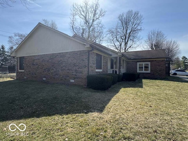 view of side of property featuring crawl space, brick siding, and a yard