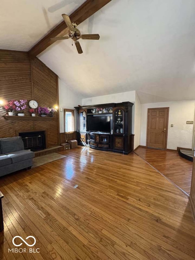 unfurnished living room with beamed ceiling, high vaulted ceiling, wood-type flooring, a brick fireplace, and ceiling fan