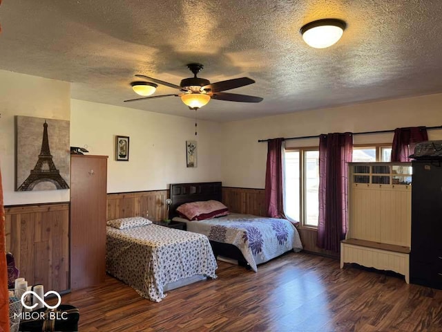 bedroom featuring wainscoting, a textured ceiling, ceiling fan, and wood finished floors