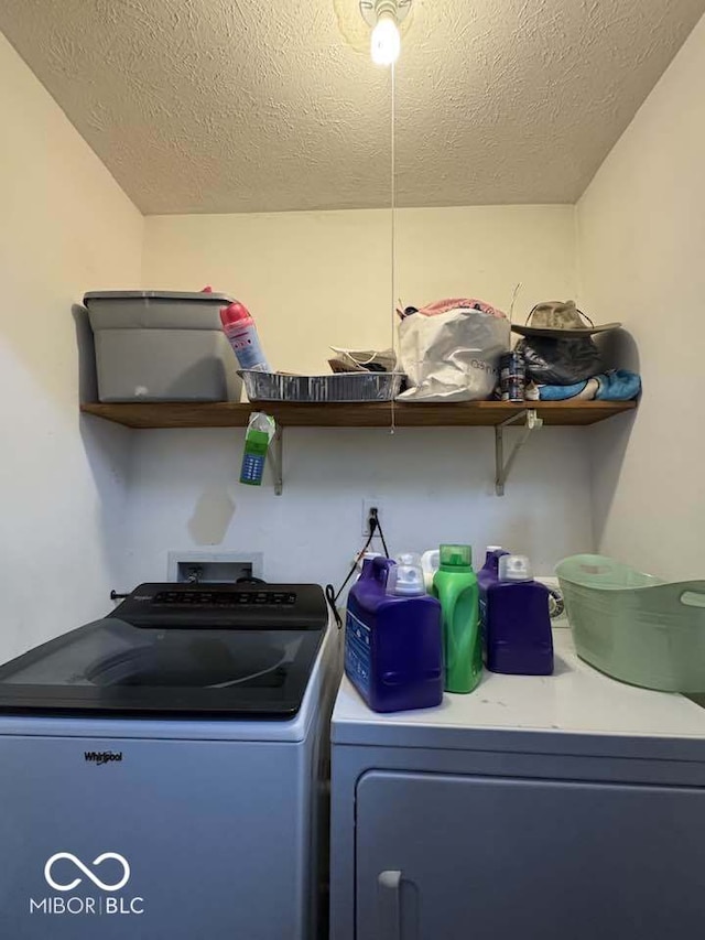 washroom with a textured ceiling, laundry area, and washer and clothes dryer