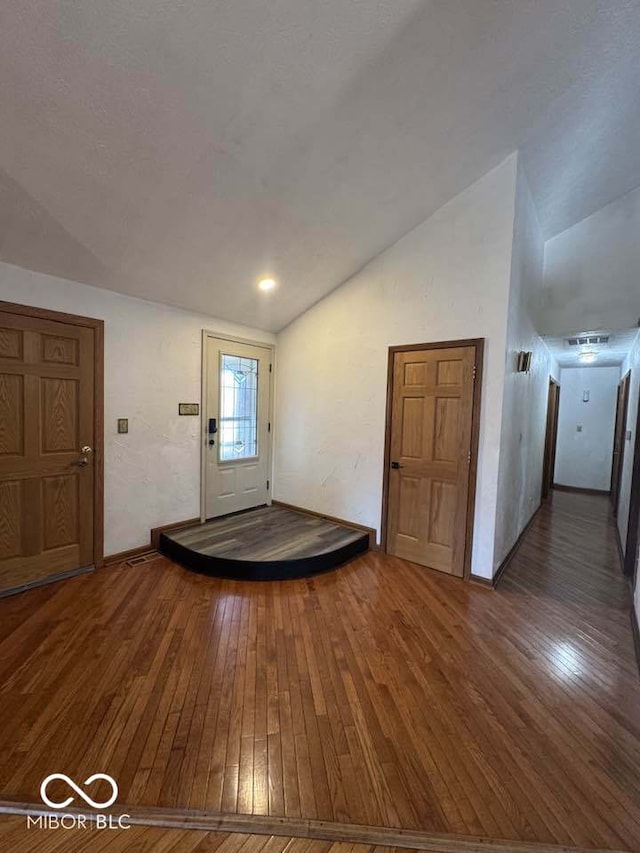 entryway with hardwood / wood-style floors and vaulted ceiling