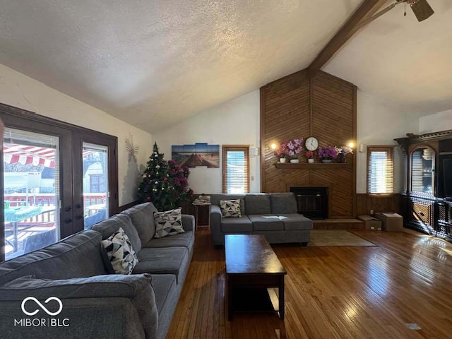 living room featuring beamed ceiling, a fireplace, hardwood / wood-style flooring, a textured ceiling, and high vaulted ceiling