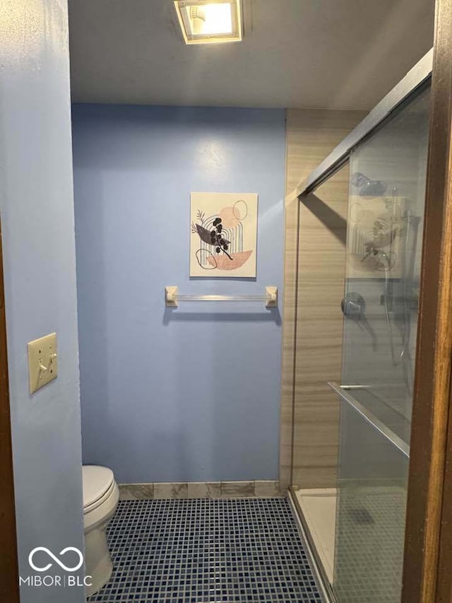 full bathroom with a stall shower, toilet, and baseboards