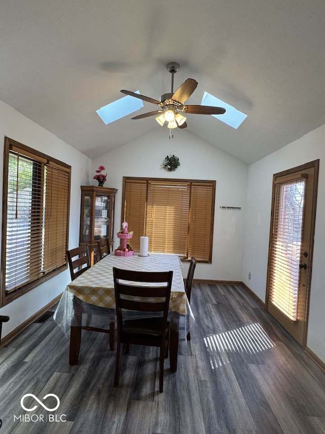 dining space featuring a ceiling fan, lofted ceiling with skylight, wood finished floors, and baseboards