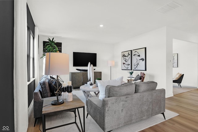 living room with light wood-type flooring, visible vents, and recessed lighting