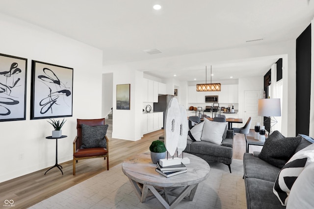 living room with recessed lighting, visible vents, and light wood finished floors