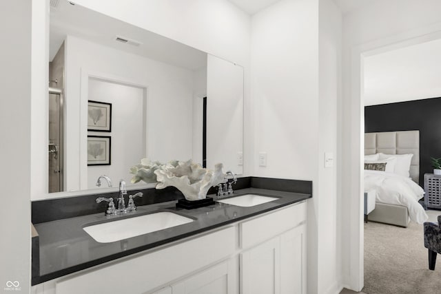 ensuite bathroom with double vanity, visible vents, connected bathroom, and a sink