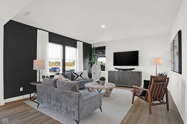 living room featuring light wood-style flooring, recessed lighting, visible vents, and baseboards