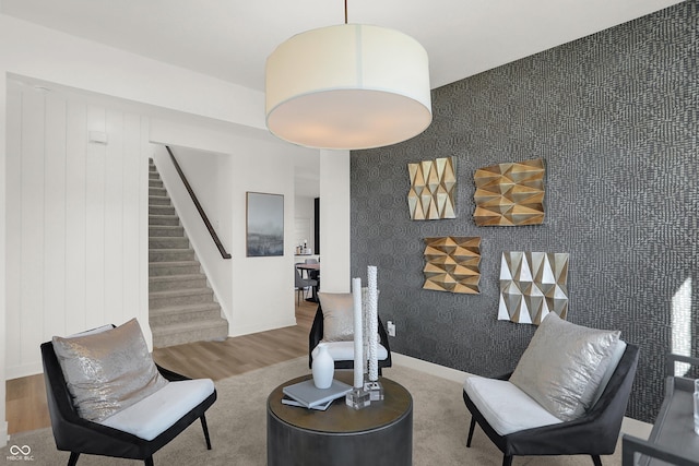 living area with baseboards, wood finished floors, and stairs