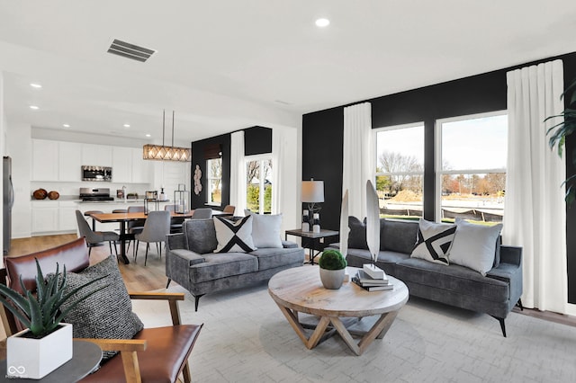 living room with light wood-style flooring, recessed lighting, visible vents, and a chandelier