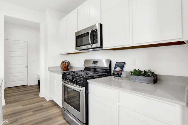 kitchen with light countertops, white cabinets, light wood-style flooring, and appliances with stainless steel finishes