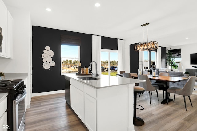 kitchen featuring light wood finished floors, light countertops, appliances with stainless steel finishes, white cabinetry, and a sink