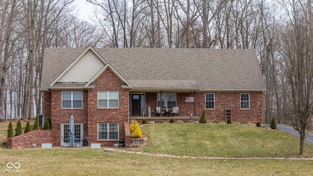 view of front facade featuring brick siding, a porch, a shingled roof, and a front lawn