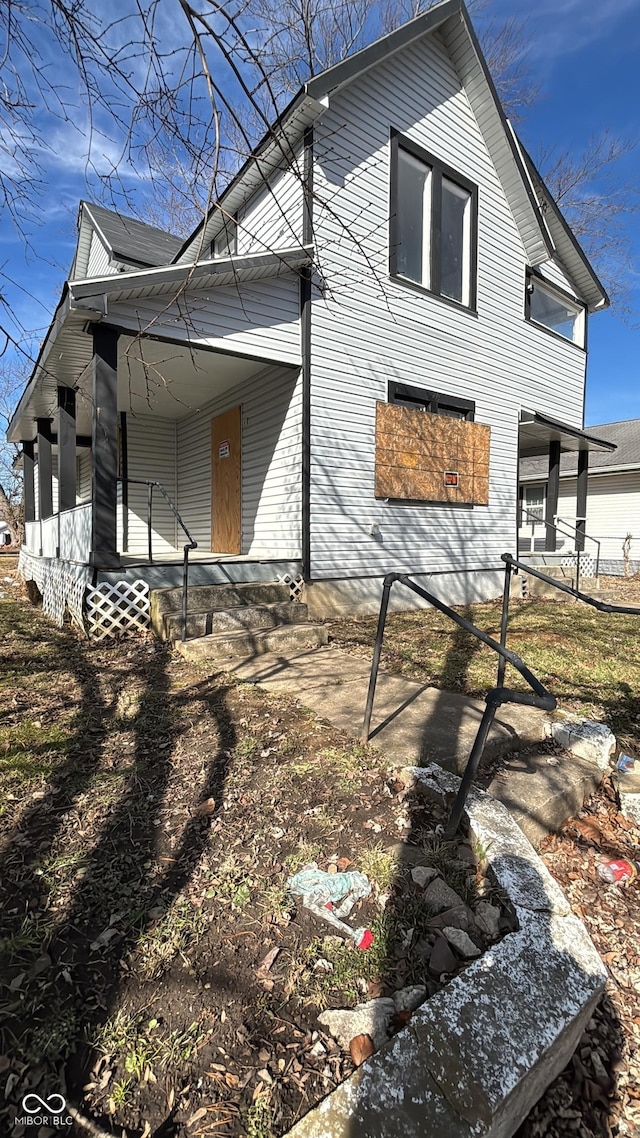 rear view of property featuring a porch and fence