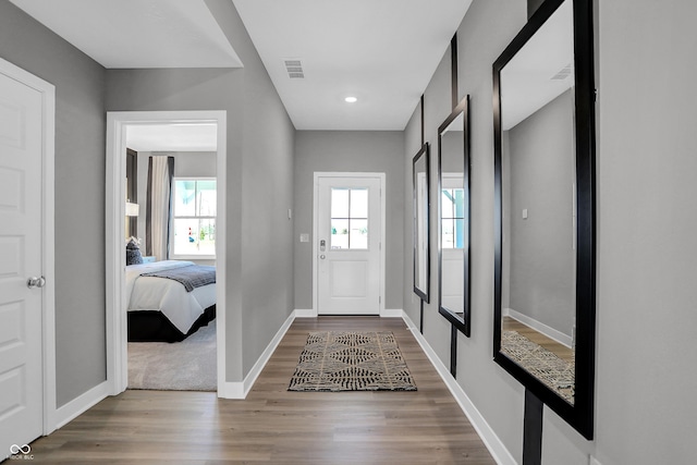 foyer entrance with visible vents, a healthy amount of sunlight, baseboards, and wood finished floors