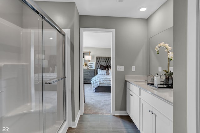 ensuite bathroom featuring baseboards, double vanity, a stall shower, a sink, and ensuite bathroom