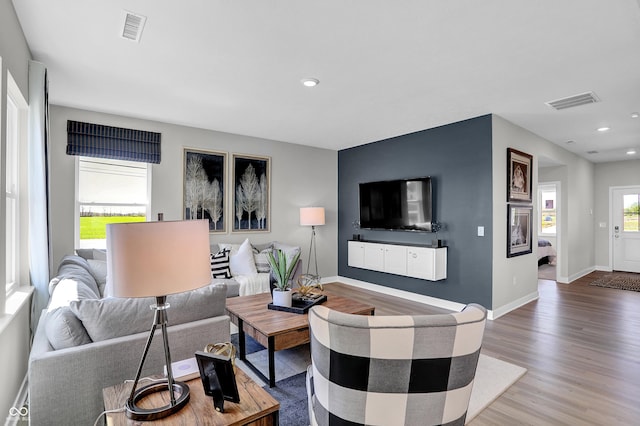 living room with recessed lighting, visible vents, baseboards, and wood finished floors