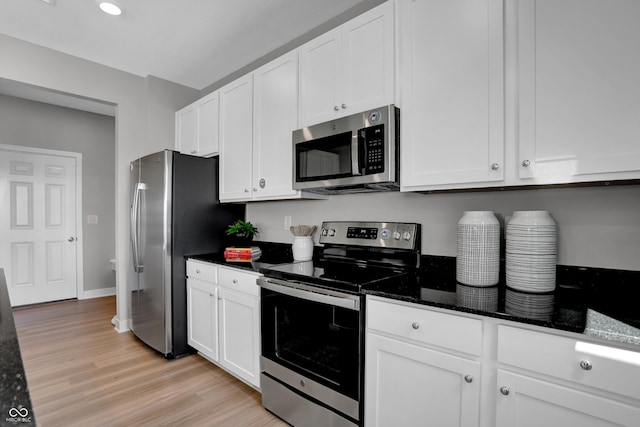 kitchen featuring baseboards, dark stone counters, stainless steel appliances, white cabinets, and light wood-style floors