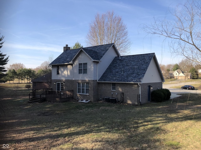 back of house with a deck, a lawn, brick siding, and a chimney