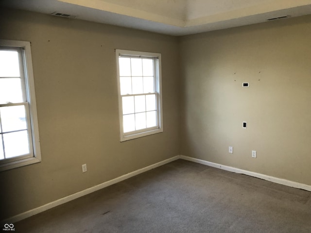 carpeted spare room with visible vents and baseboards