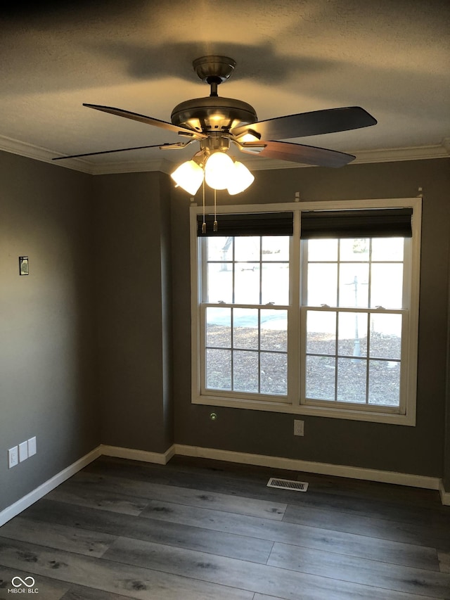 empty room featuring a healthy amount of sunlight, visible vents, and ornamental molding