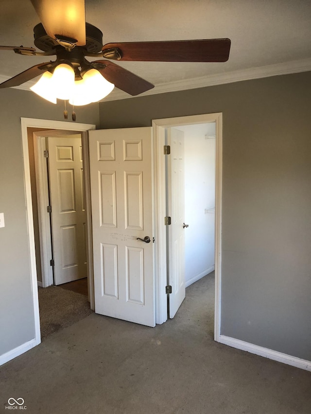 unfurnished bedroom featuring baseboards, carpet, ceiling fan, and crown molding