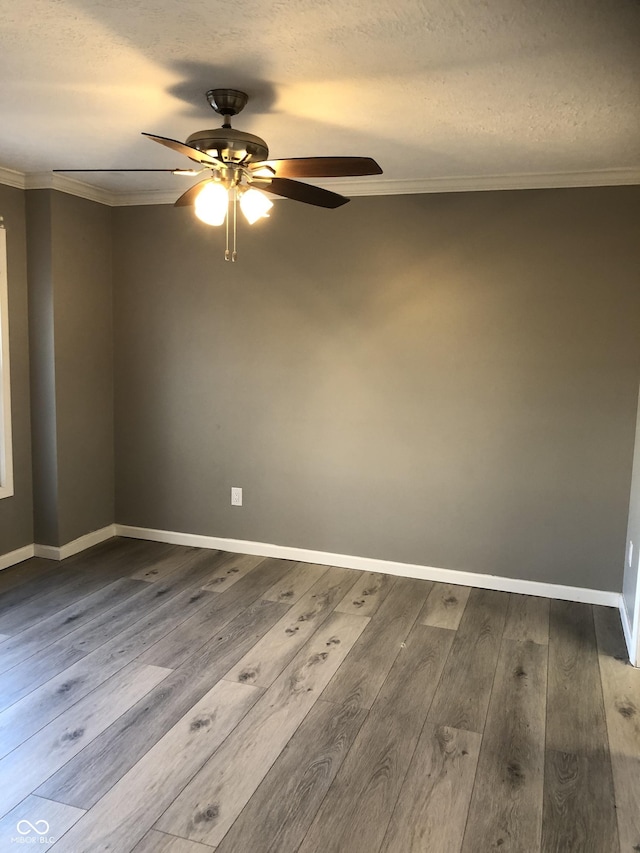 unfurnished room with crown molding, baseboards, dark wood-style flooring, and ceiling fan