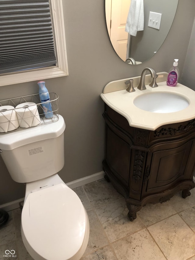 half bathroom with vanity, toilet, and baseboards