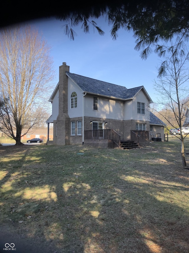 back of property featuring a wooden deck, a lawn, and a chimney