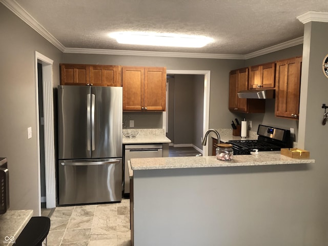 kitchen with under cabinet range hood, a peninsula, stainless steel appliances, and ornamental molding