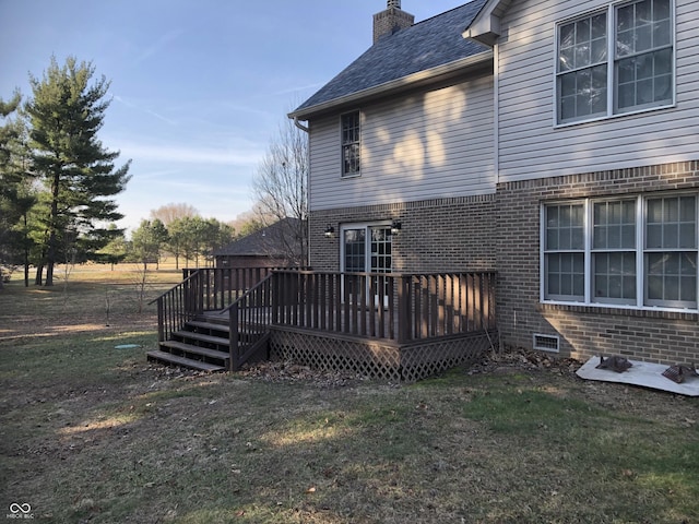 back of house with a yard, brick siding, a deck, and a chimney