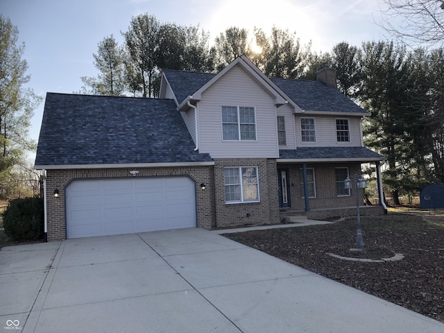 traditional home featuring driveway, roof with shingles, an attached garage, brick siding, and a chimney