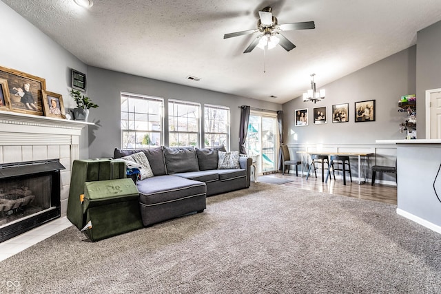 living area with visible vents, lofted ceiling, carpet flooring, ceiling fan with notable chandelier, and a tile fireplace