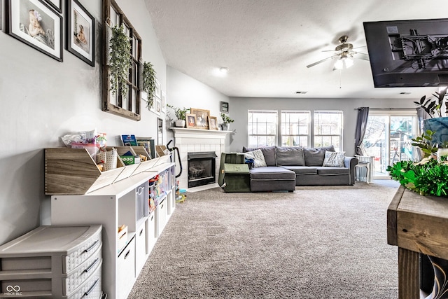 living area featuring visible vents, a textured ceiling, carpet, a fireplace, and ceiling fan