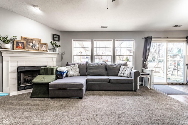 living room with a textured ceiling, visible vents, and a tile fireplace