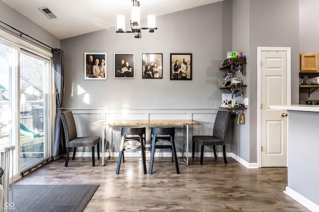 dining space featuring visible vents, breakfast area, lofted ceiling, wood finished floors, and a notable chandelier