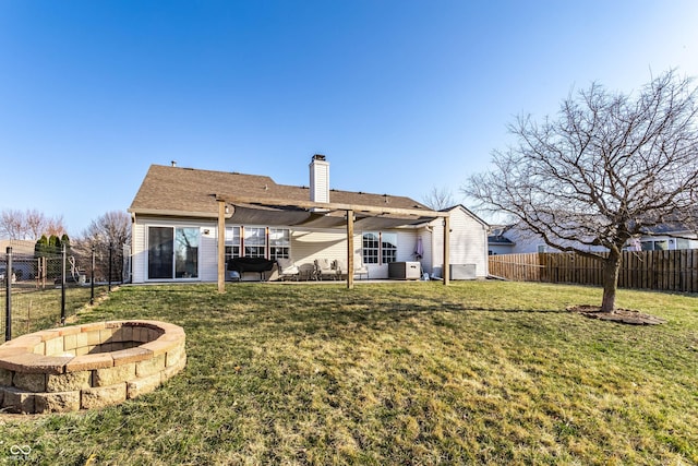 rear view of property featuring a fire pit, a chimney, a fenced backyard, and a lawn